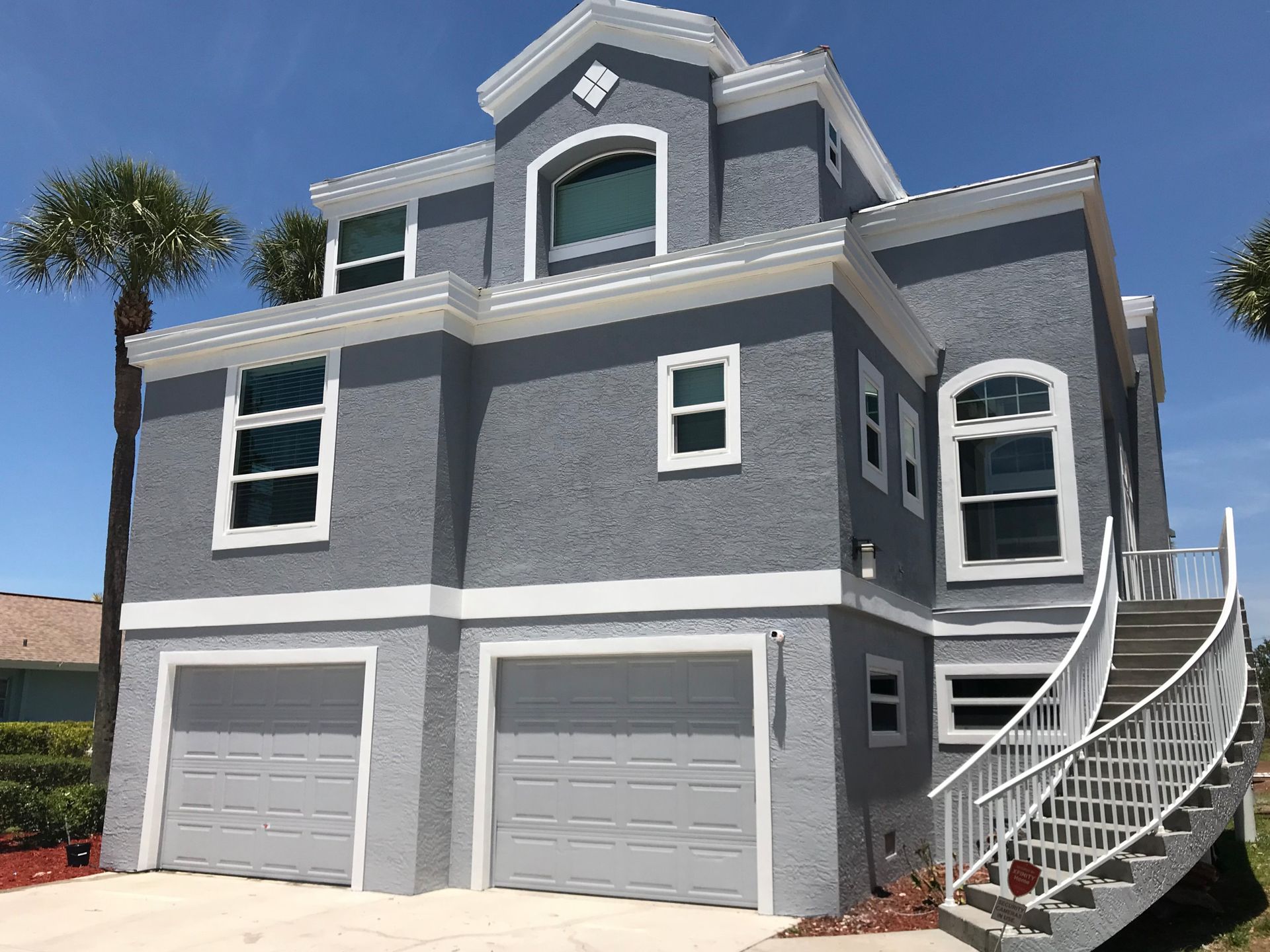 A large gray house with stairs leading up to it