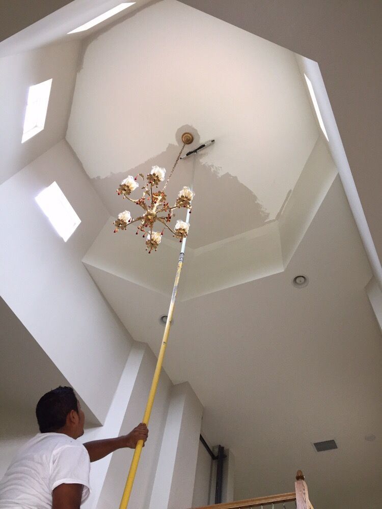 A man is painting a ceiling with a roller