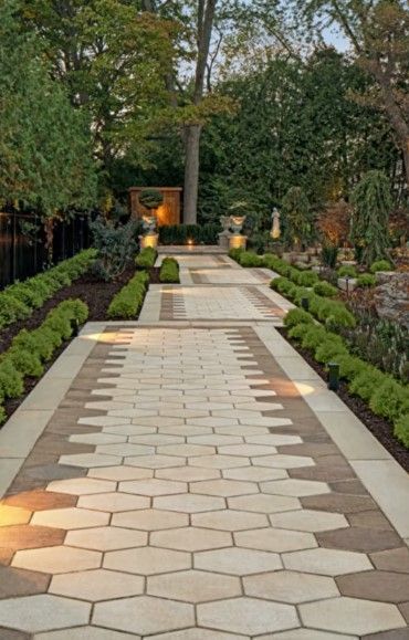A stone pathway made of interlocking brown pavers, lined with green foliage and palm fronds on either side.
