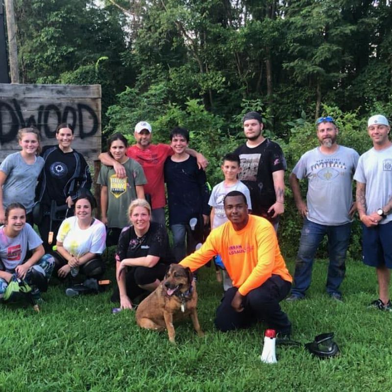 A group of men are posing for a picture while playing paintball.