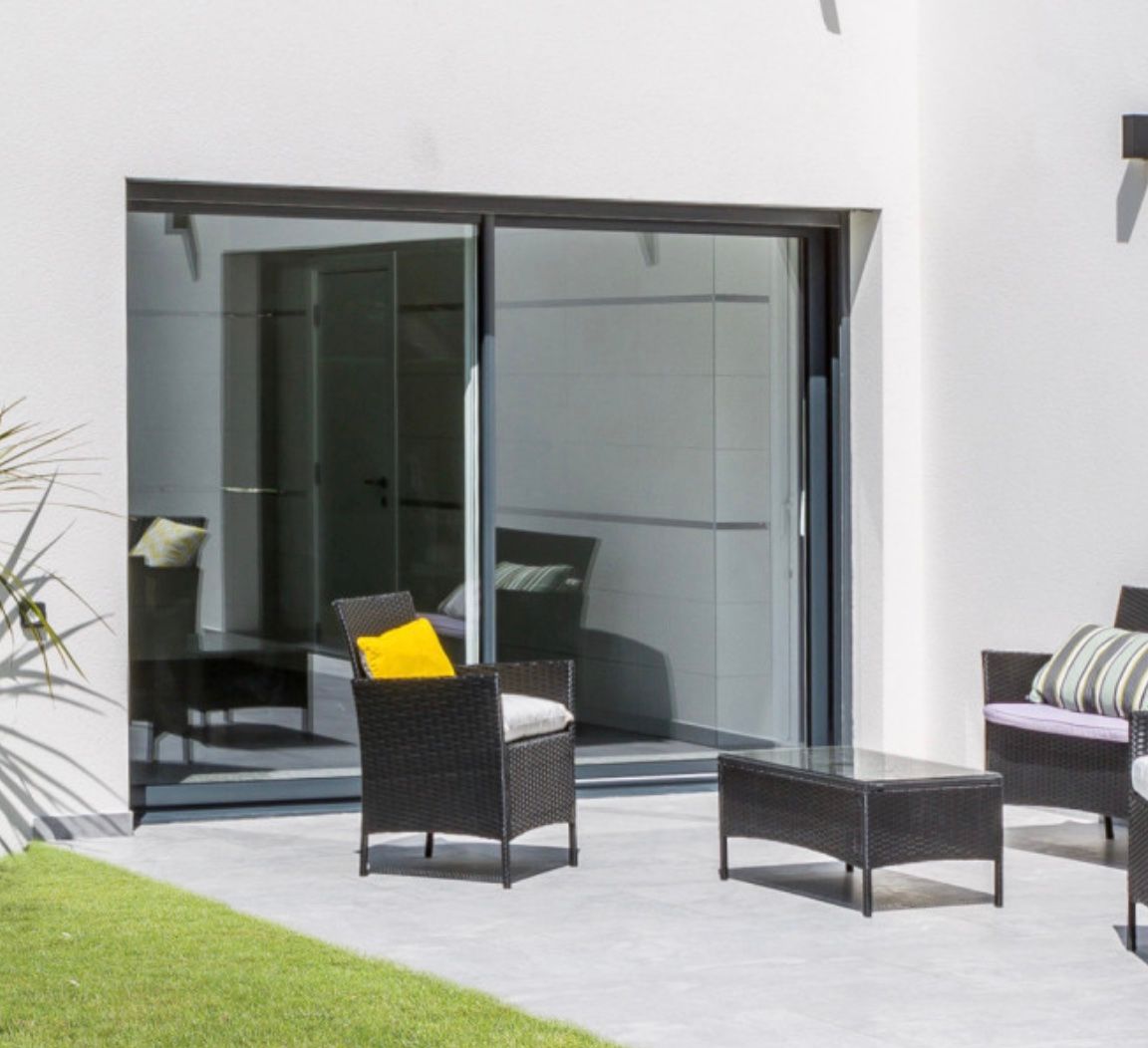 Un patio avec des meubles en osier et une porte coulissante en verre