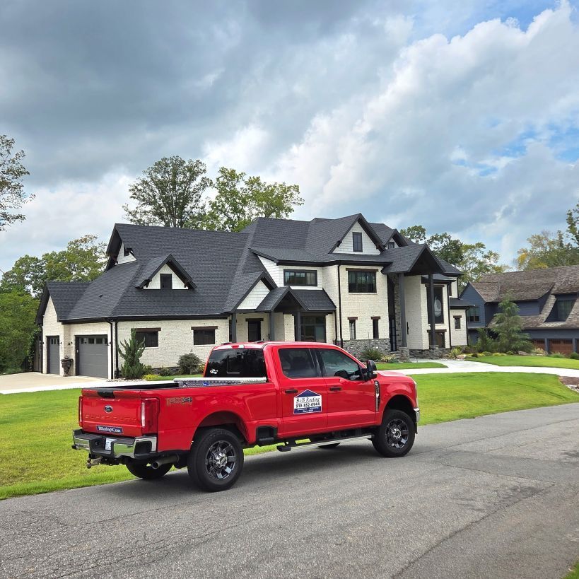 Red pickup truck parked on a residential street in front of a large house under a cloudy sky