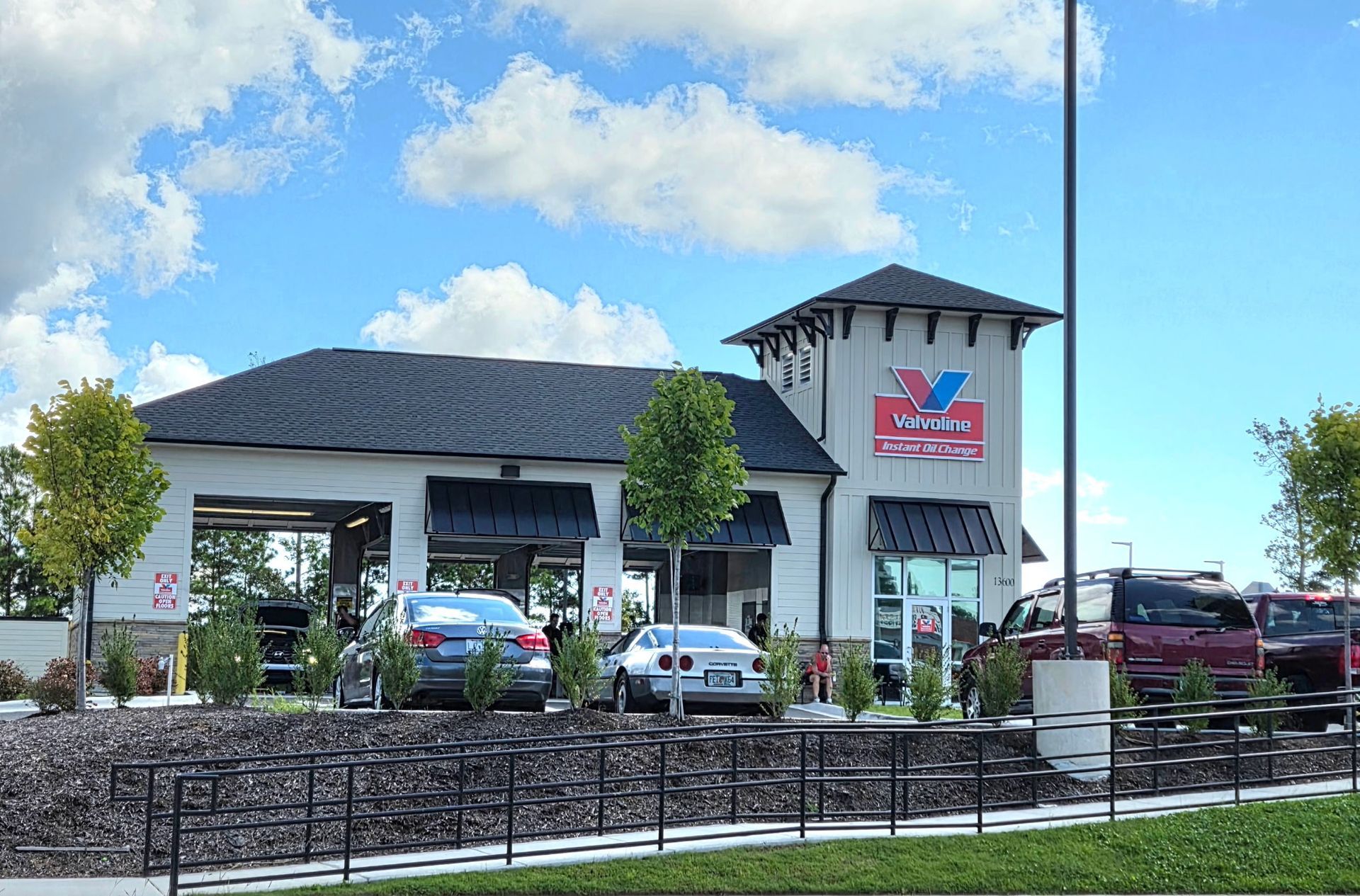 Modern commercial building with cars parked outside under a blue sky