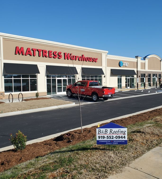 Mattress Warehouse storefront, red pickup truck, B&B Roofing sign in Sanford NC.