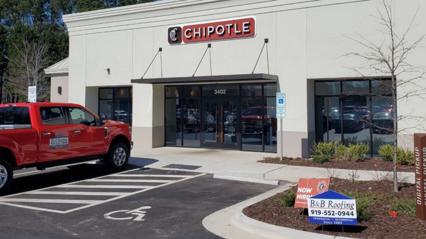 Chipotle restaurant storefront with a red Jeep parked outside and a curbside pickup sign in Sanford NC.