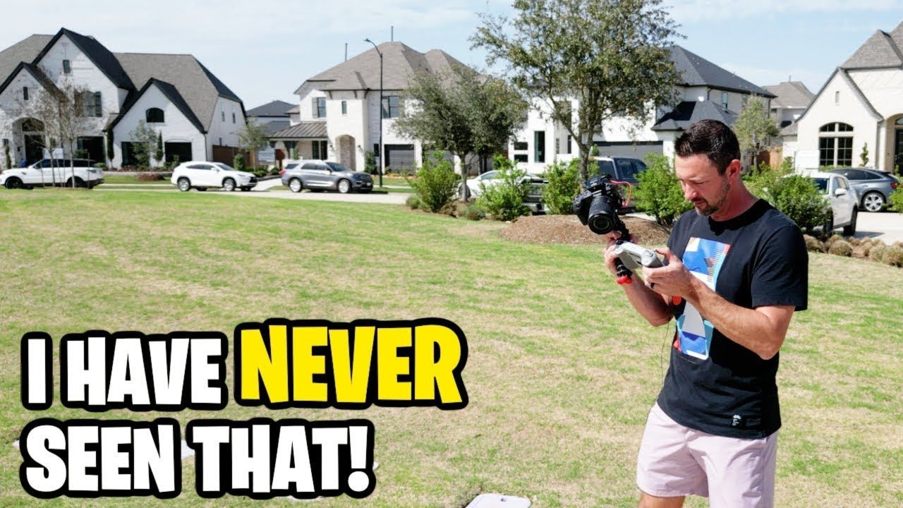 A man is standing in a grassy field holding a camera.