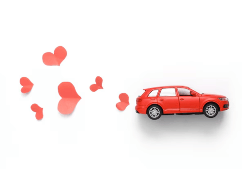 Red toy car with red hearts floating beside it on a white background