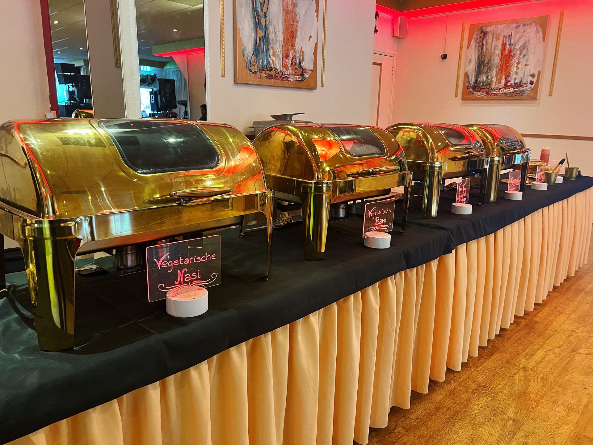 Gouden buffetschalen op een tafel met een zwart tafelkleed en een beige tafelrok.
