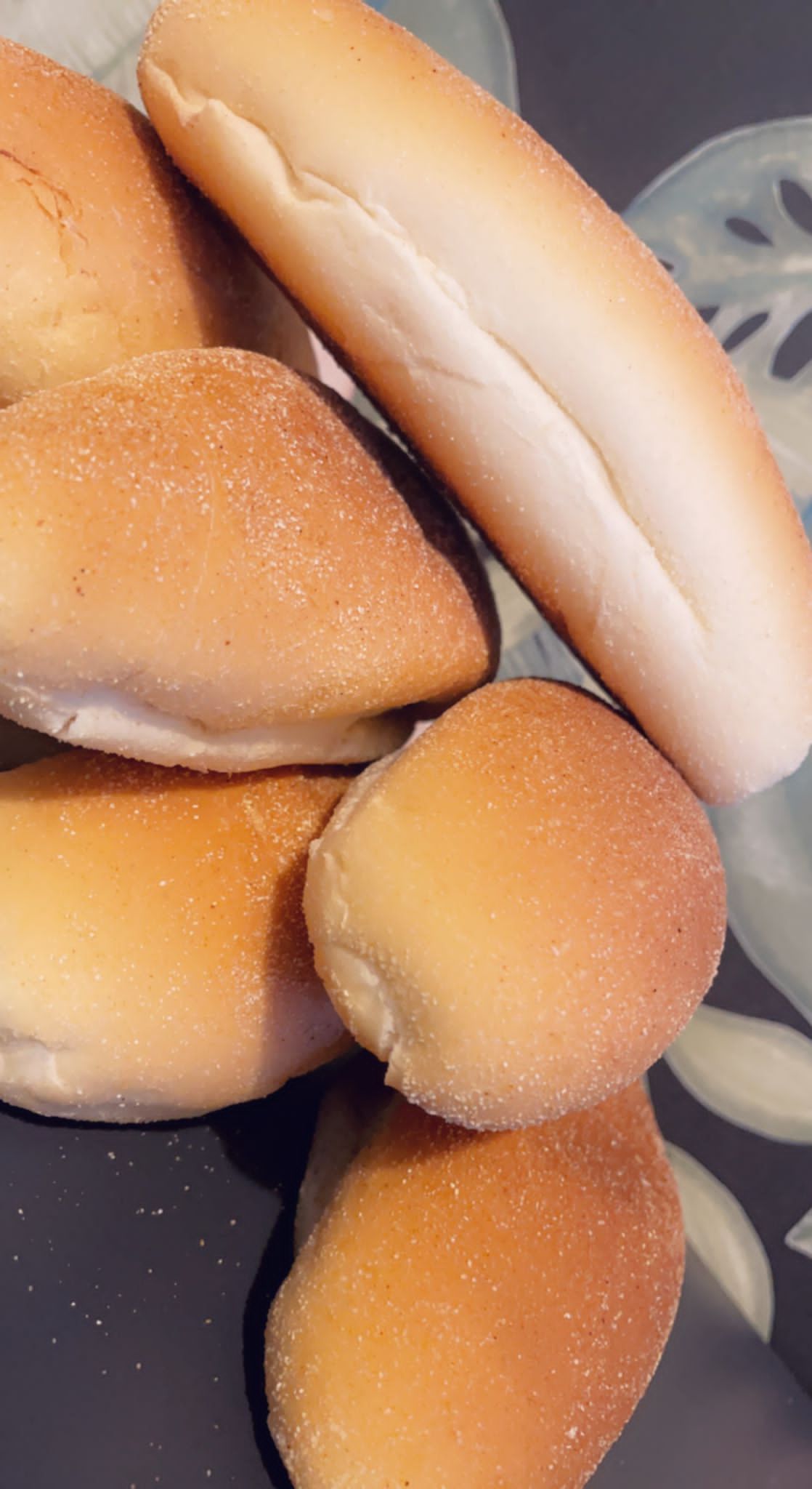 Close-up van goudbruine broodjes en een hotdogbroodje op een bord met een patroon.