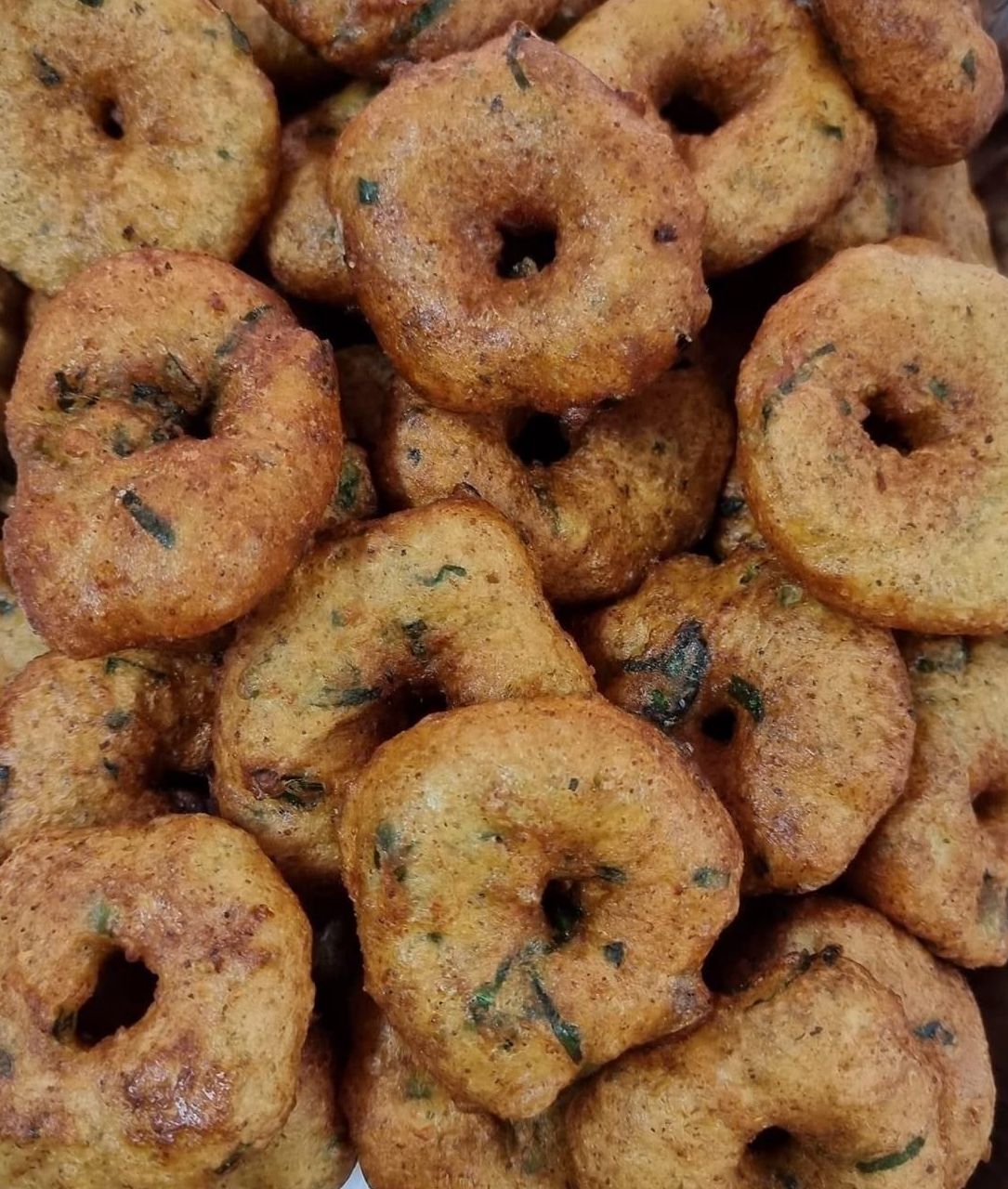 Een stapel goudbruine, ringvormige vada's, een hartige snack uit Zuid-India.