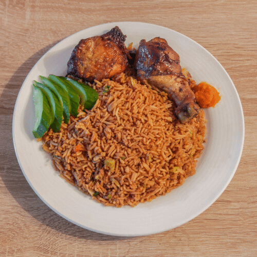 Een bord jollofrijst met kip en plakjes avocado.