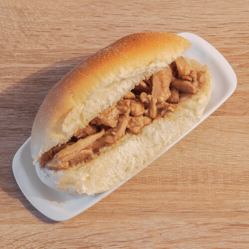 Kipsandwich op een wit bord, geplaatst op een houten ondergrond.