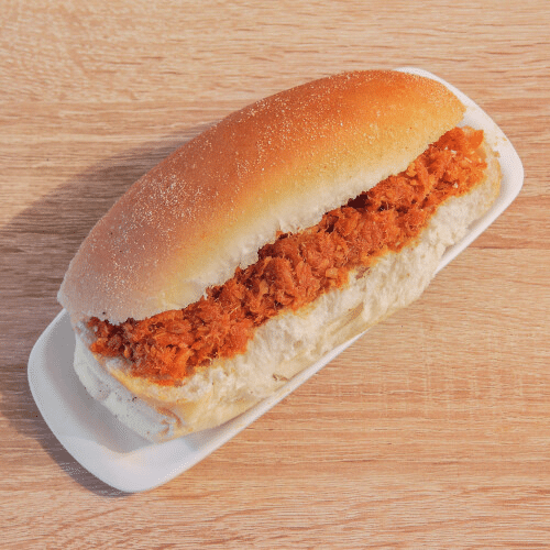 Een sandwich met sinaasappelvulling op een klein wit bordje, geplaatst op een houten ondergrond.