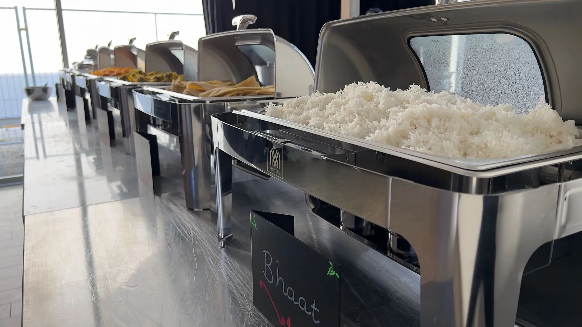 Buffet met diverse warme gerechten in roestvrijstalen warmhoudschalen.