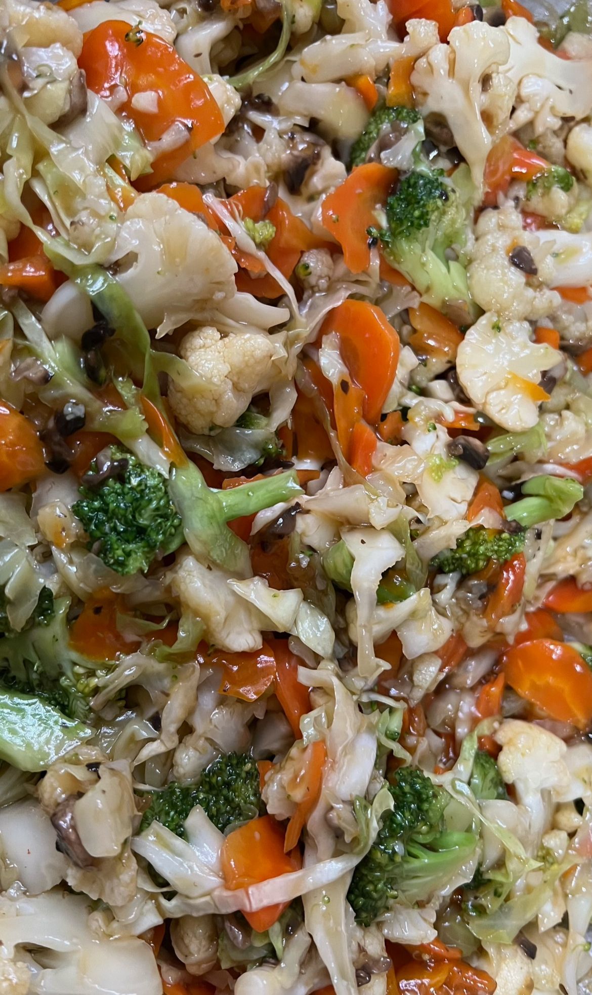 Kleurrijk gewokte groenten, waaronder broccoli, wortelen, bloemkool en kool.