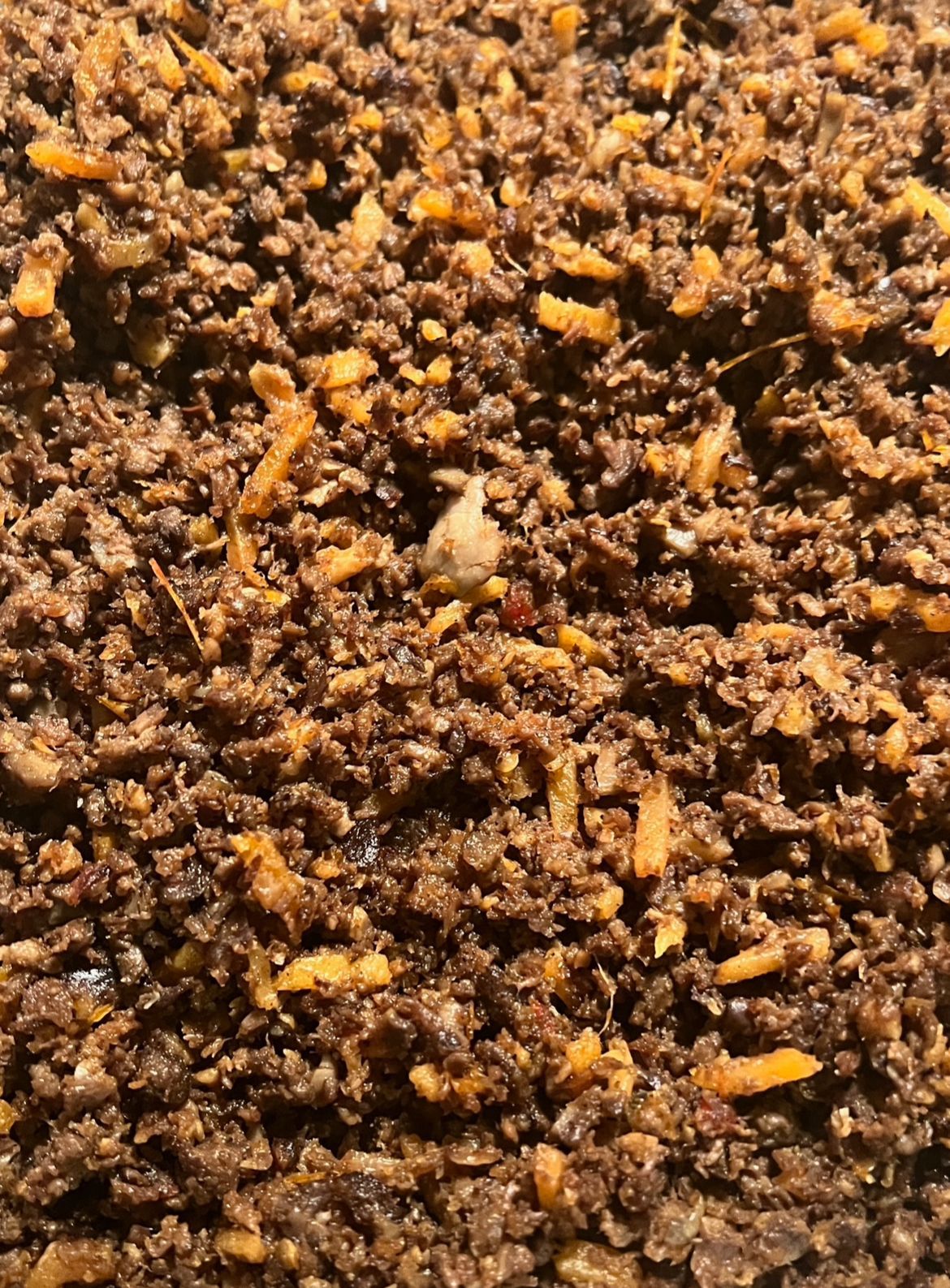 Detailopname van bruin, korrelig materiaal met gele vlekjes en een enkel, gebroken wit stukje.