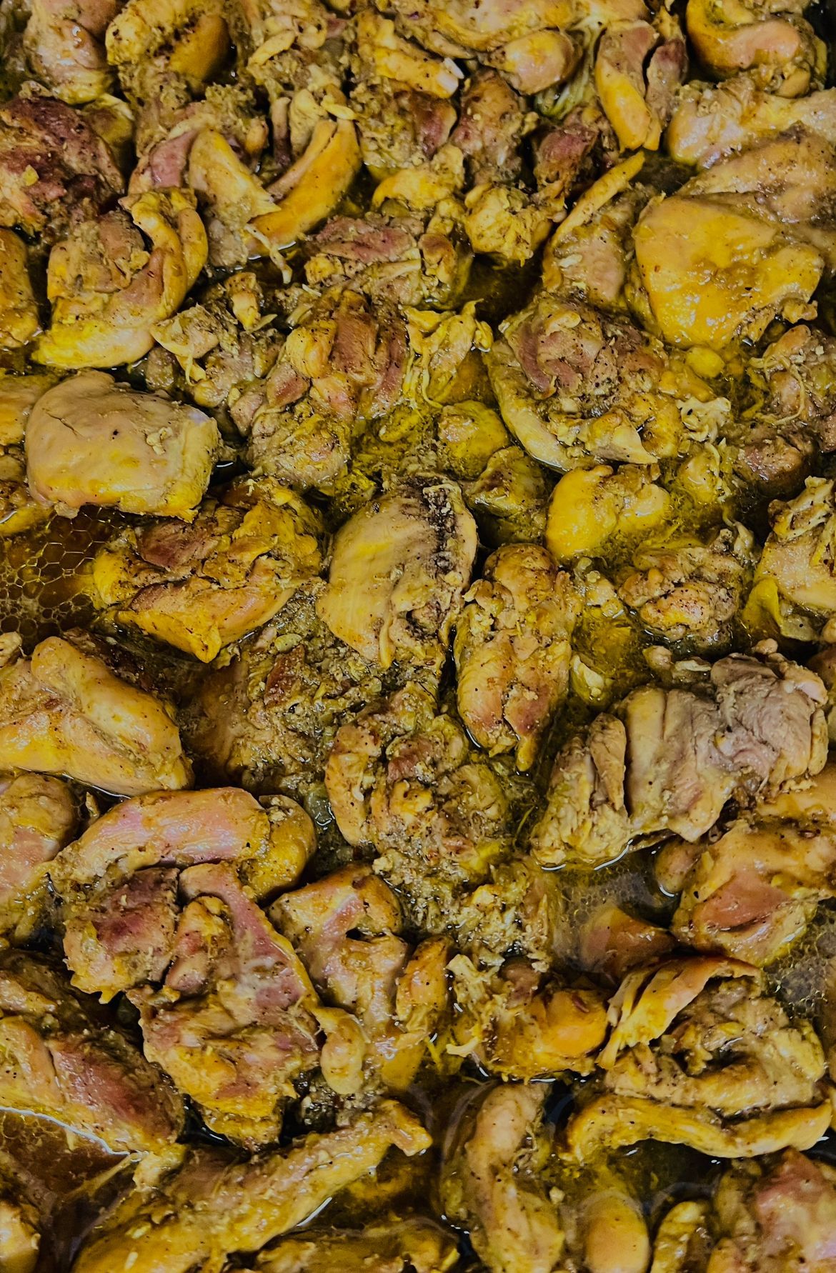 Close-up van gekookte kipstukjes bedekt met een gele kruidenmix.