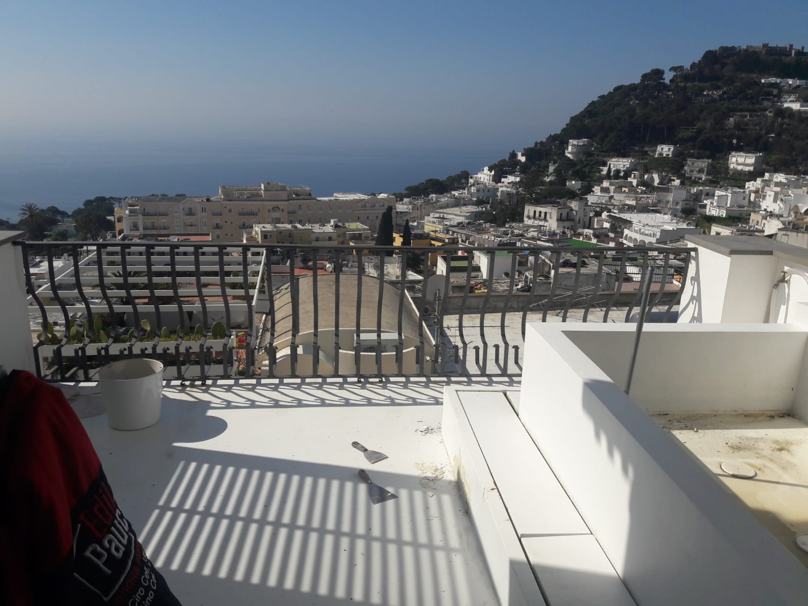 White terrace overlooking the sea and hillside town under a clear blue sky