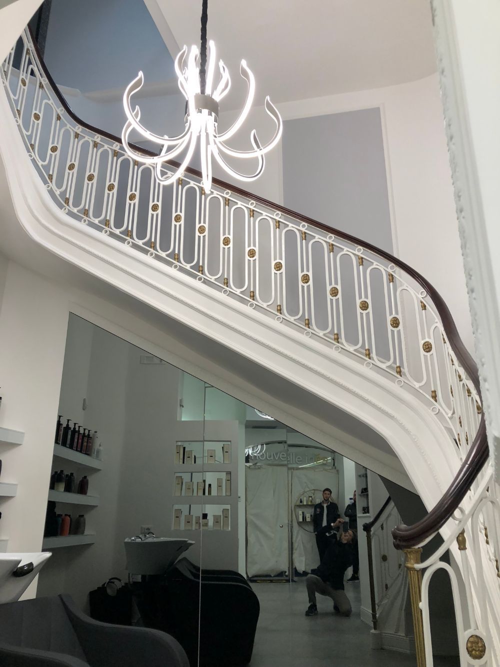 Elegant curved staircase with white railing and chandelier in a bright interior foyer