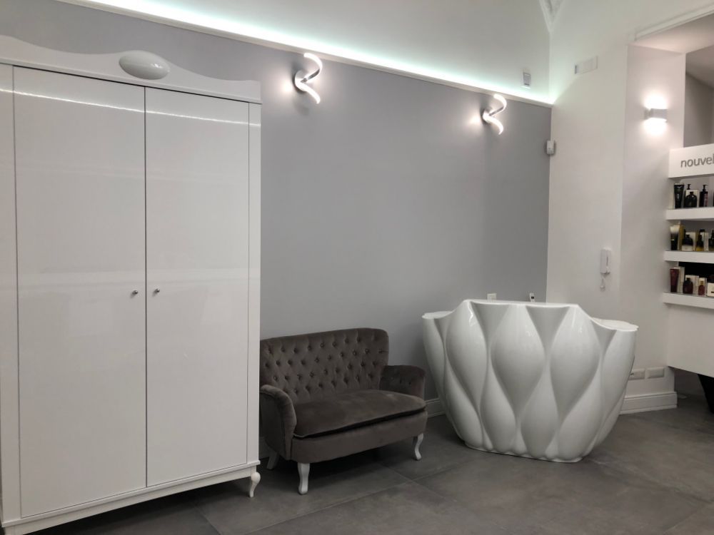 Modern salon interior with white cabinets, gray tufted loveseat, and white reception desk