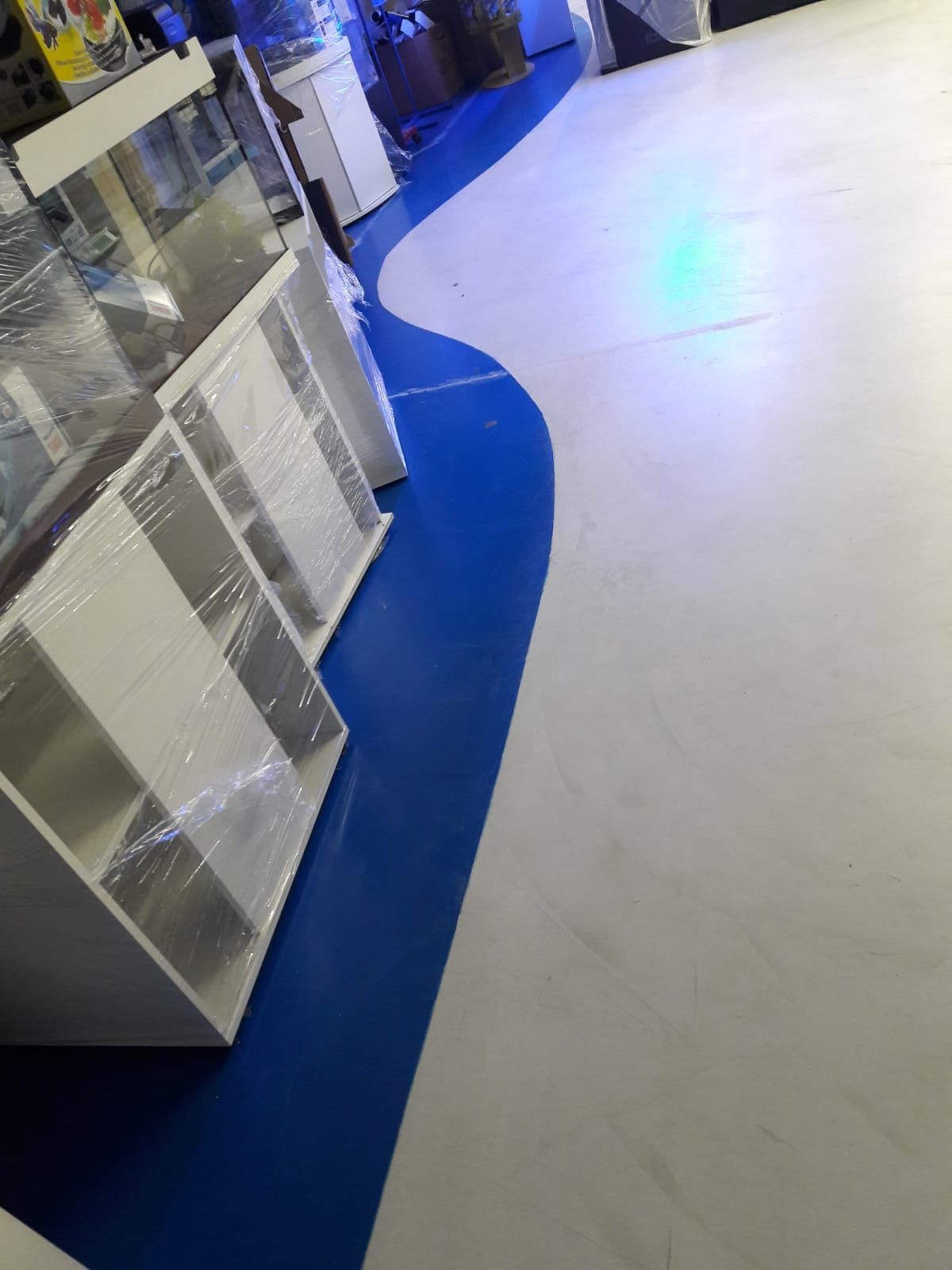 Store aisle with white cabinets and a blue curved floor border under bright lights