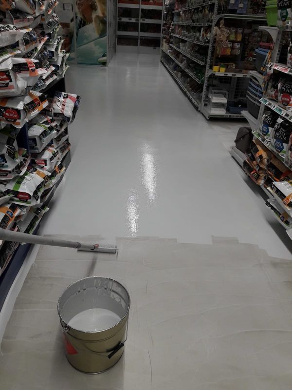 Aisle in a store with shelves on both sides and a bucket on the floor near the foreground.