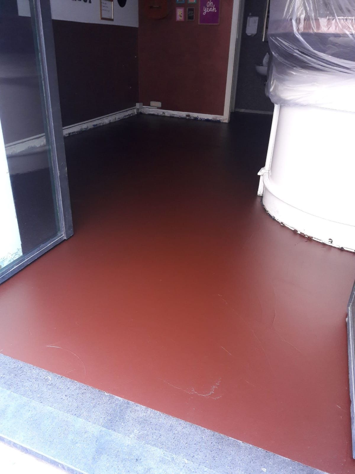 Empty indoor room with red floor, dark walls, and a white cylindrical object on the right