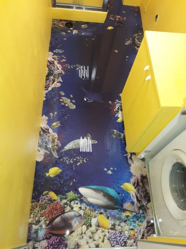 Narrow hallway with bright yellow walls and blue fish-patterned floor, beside a washing machine.
