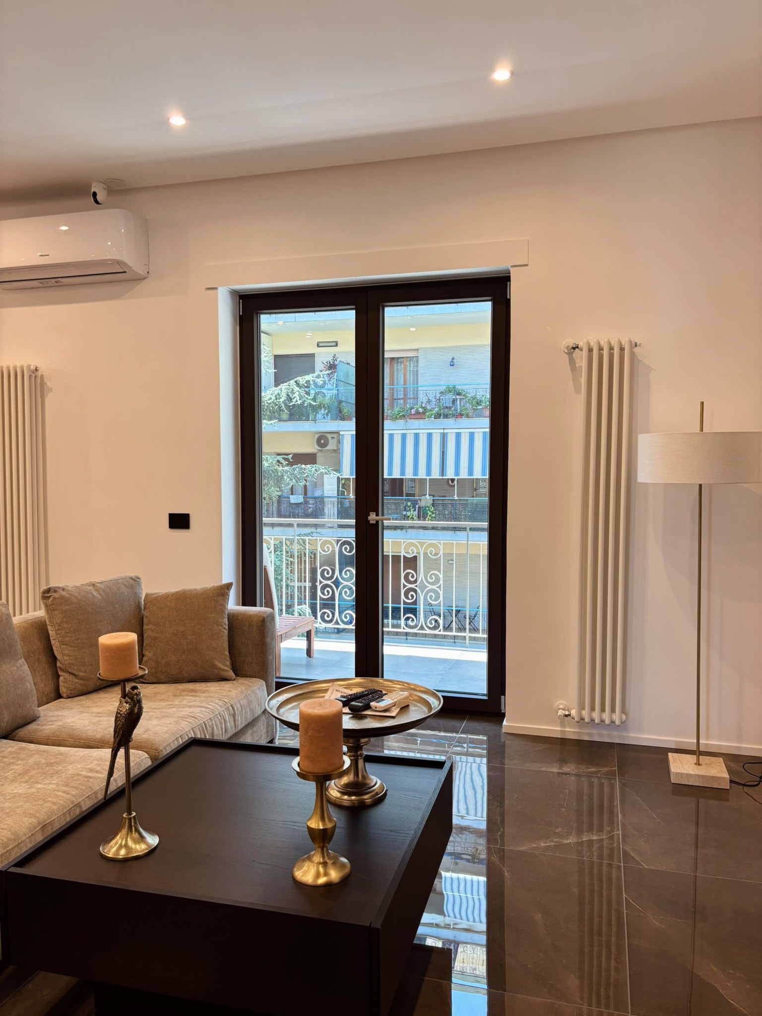 Modern living room with gray sofa, black coffee table, floor lamp, and glass doors to a balcony