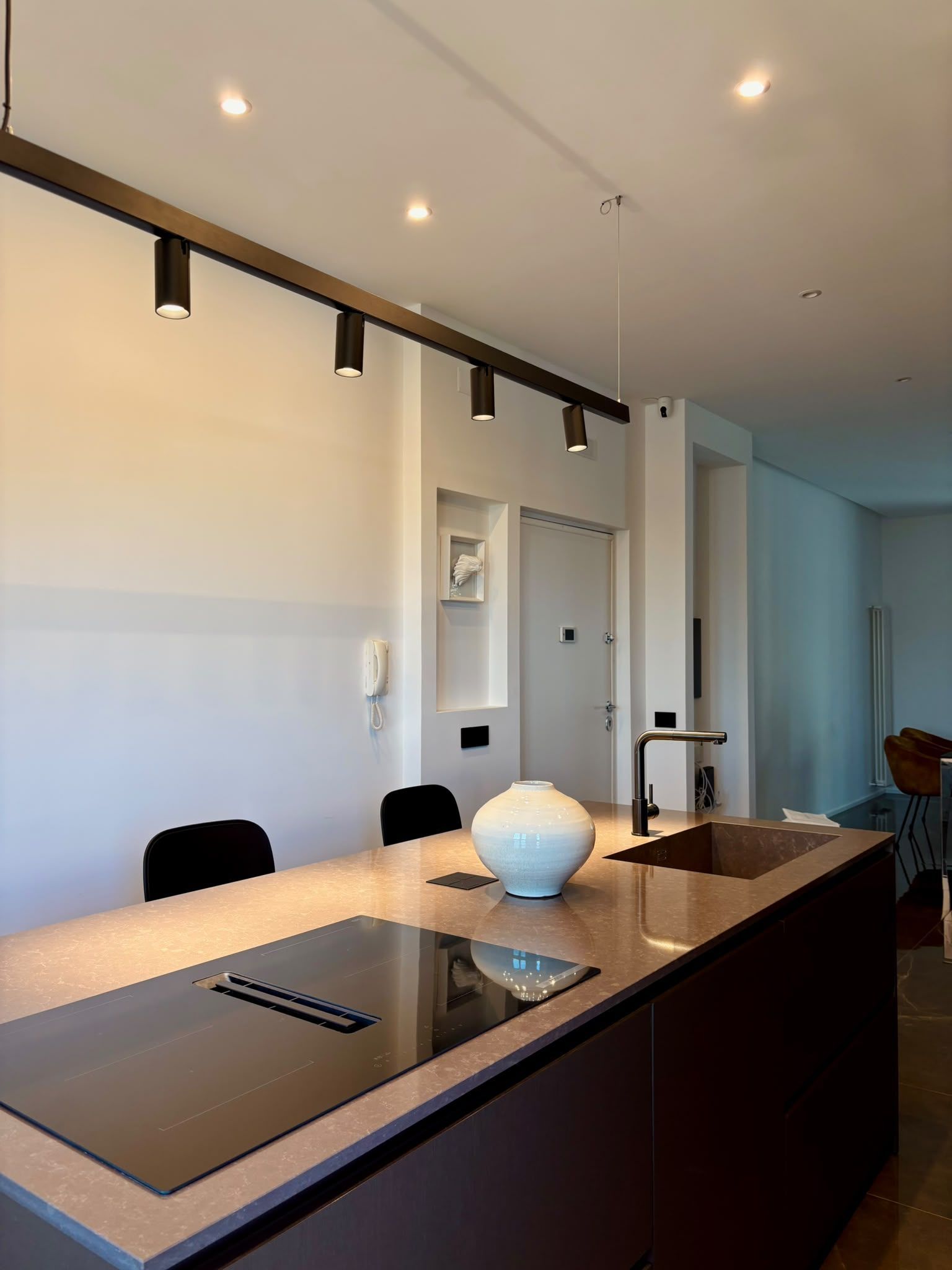 Modern kitchen with island cooktop, white cabinetry, and track lighting
