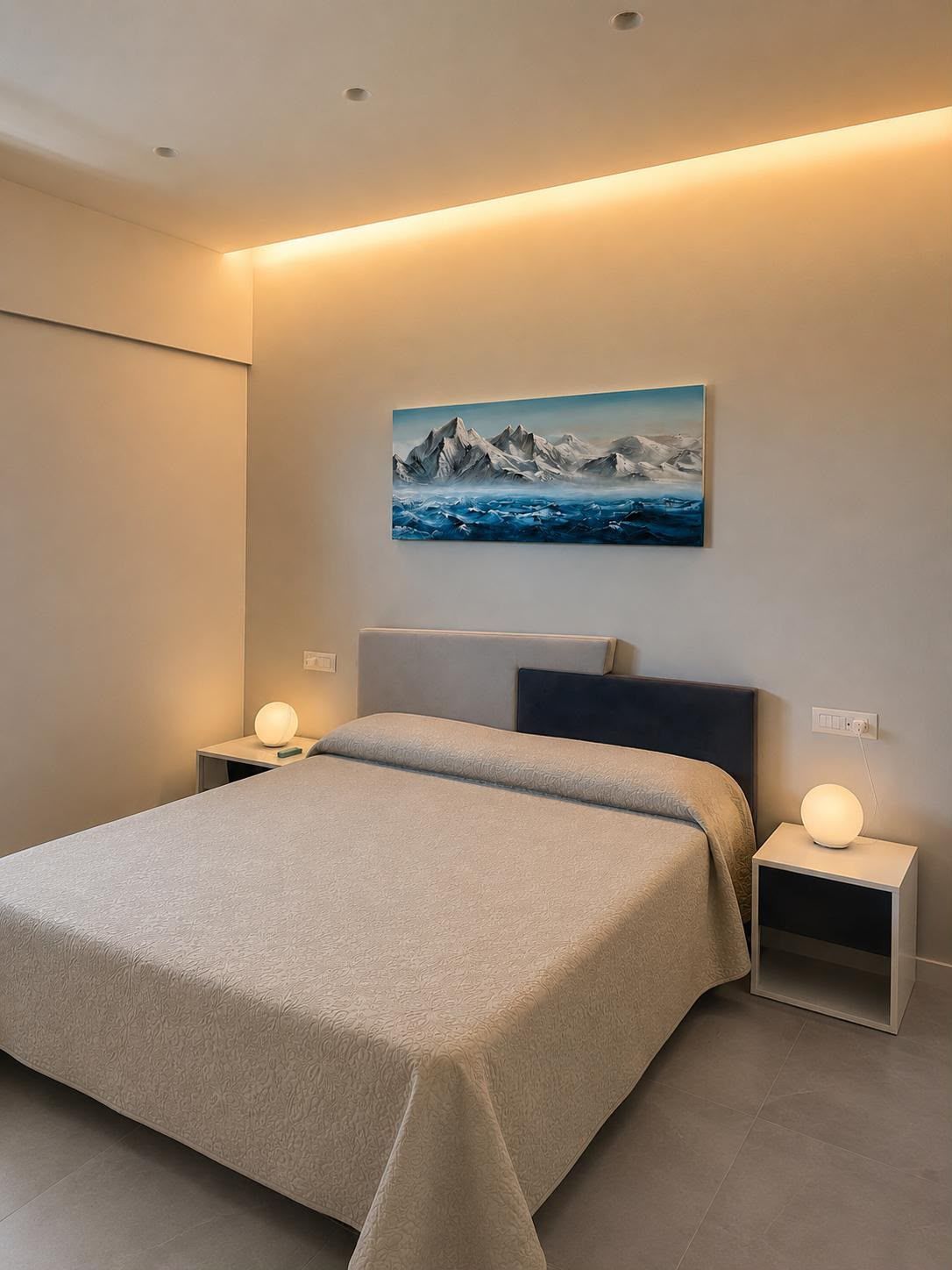 Modern bedroom with a double bed, bedside lamps, and mountain landscape wall art