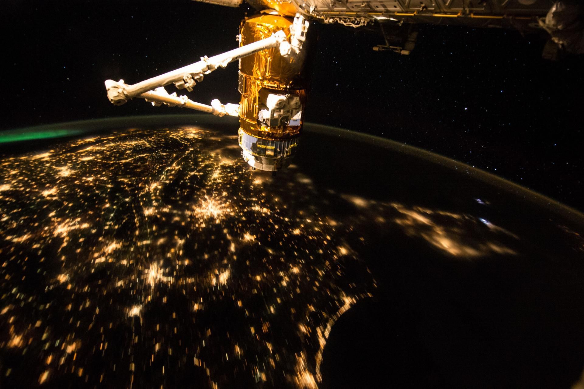 Earth at night seen from the International Space Station, city lights below the solar arrays