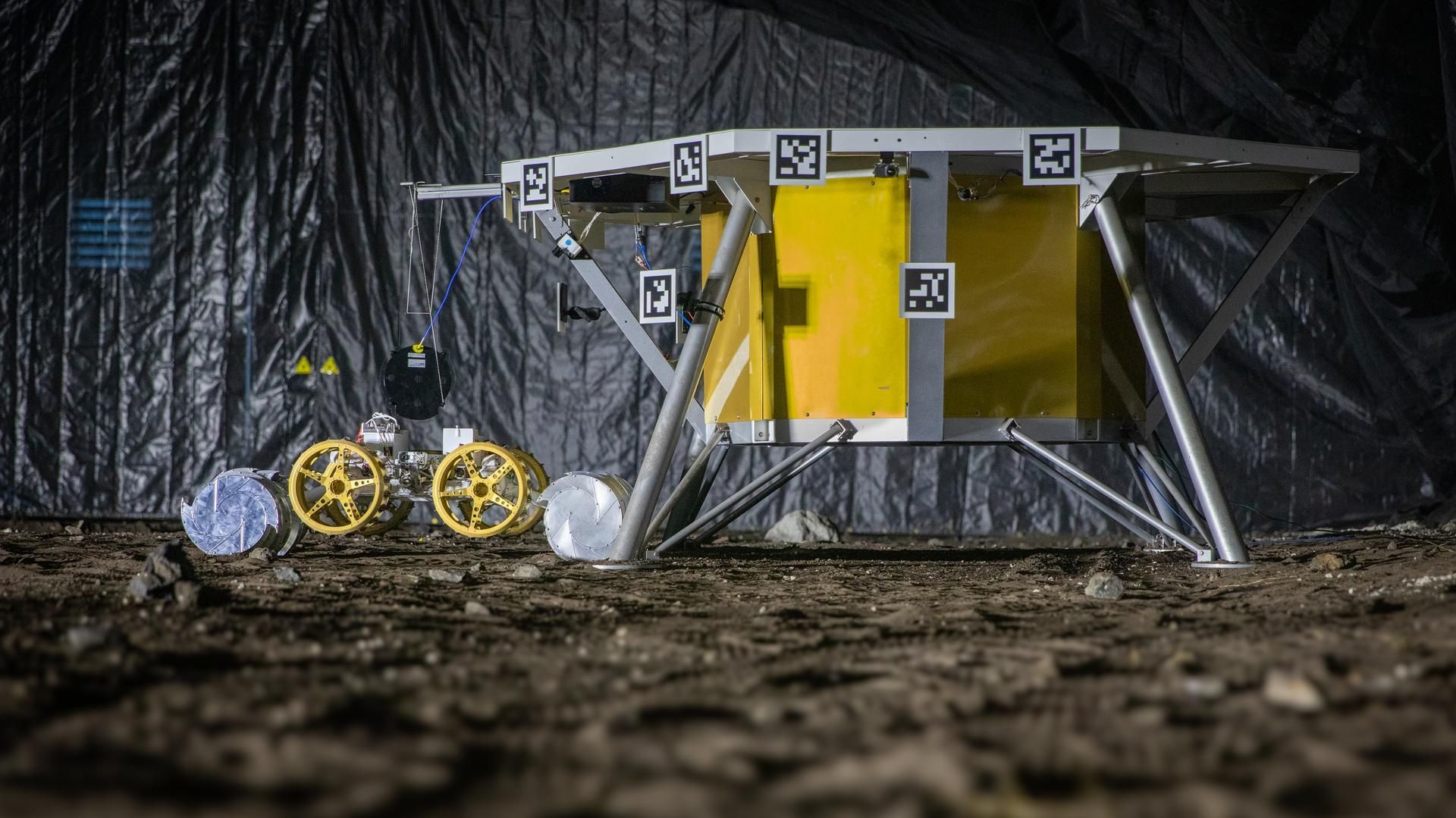 An excavator running a simulated lunar mission across a regolith test bed