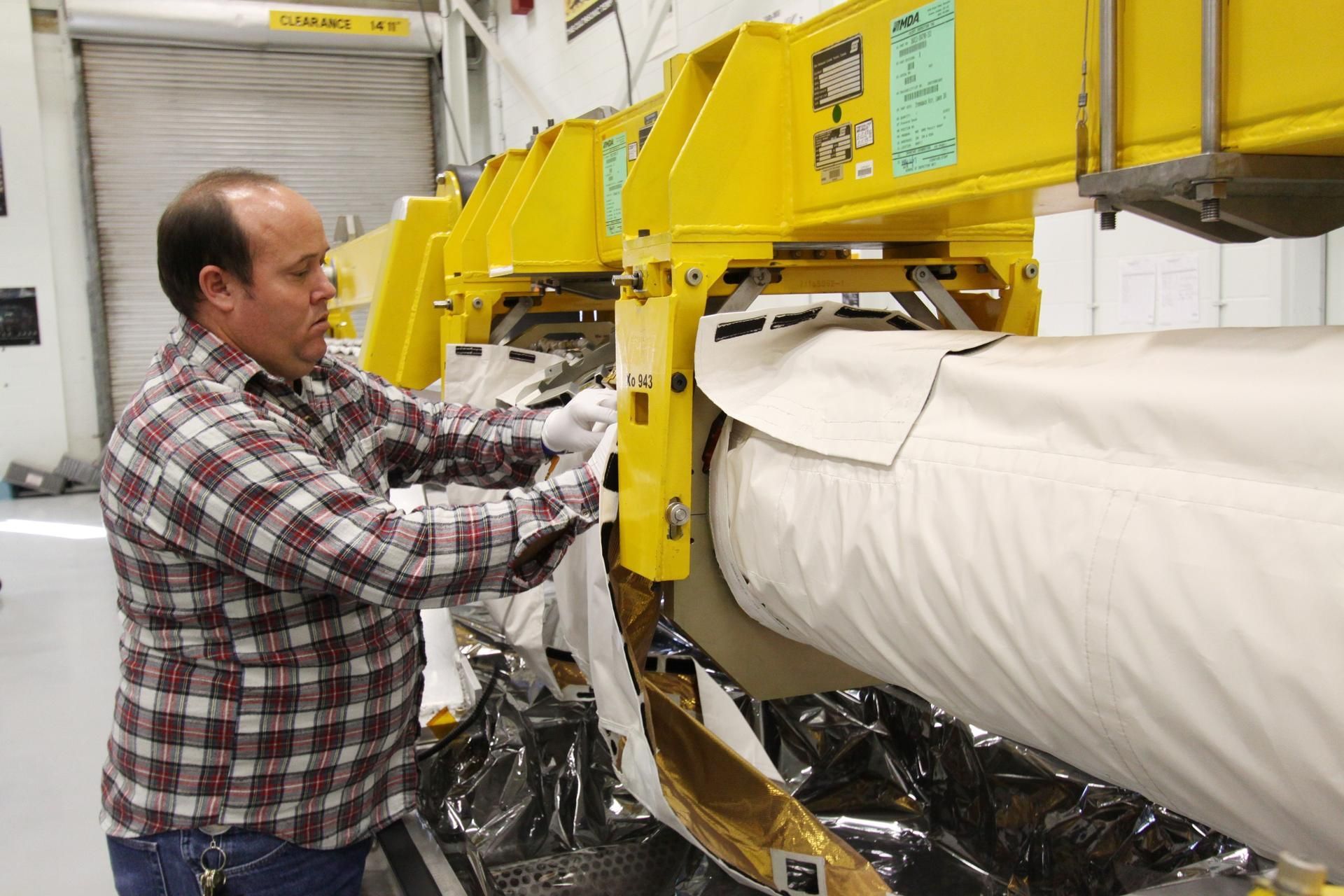 A technician working on flight hardware in a manipulator systems laboratory