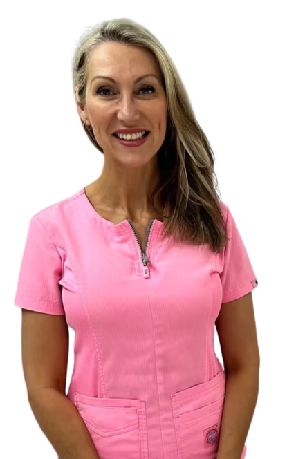A woman is wearing a pink scrub top and smiling.