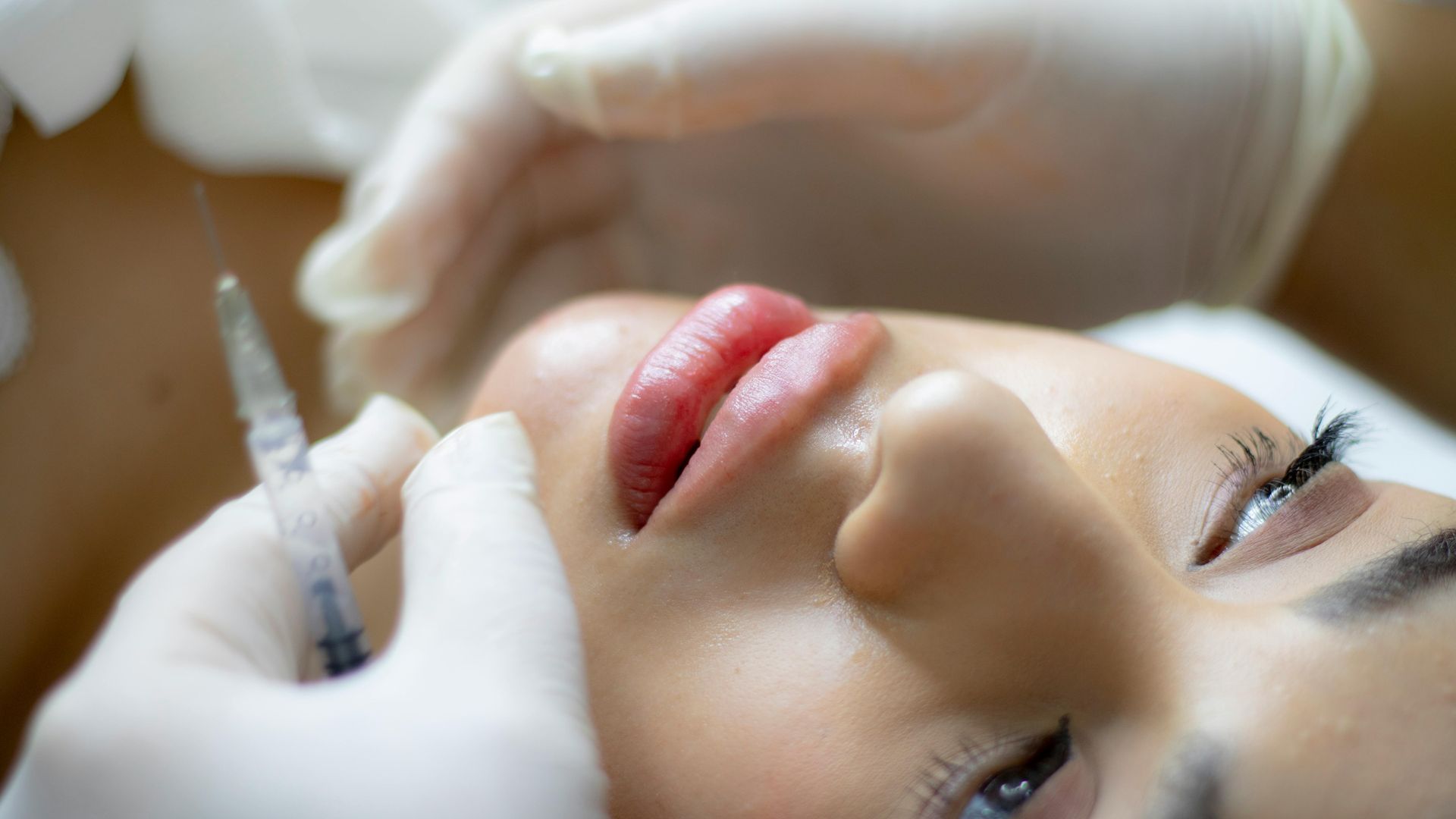 A woman is getting a botox injection in her lips.