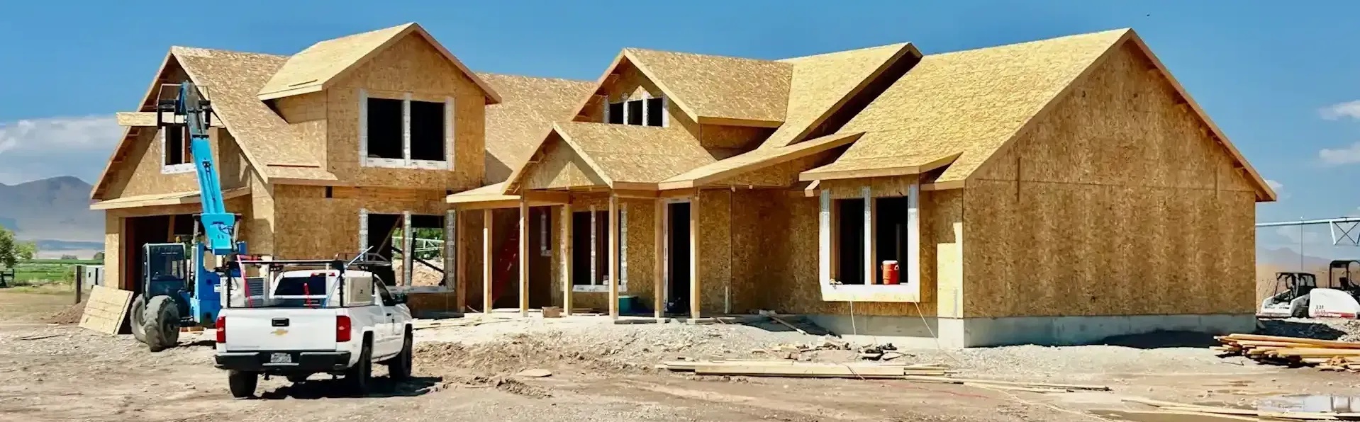 A truck is parked in front of a house under construction.