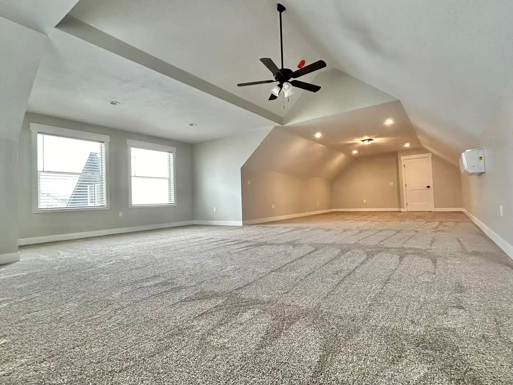 An empty room with a ceiling fan and a lot of windows.