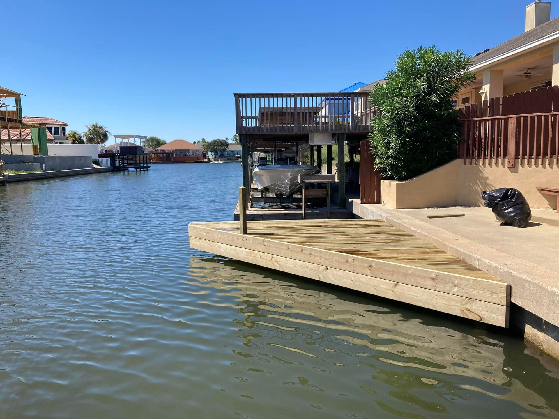 Waterfront home with dock and boat on a canal under a sunny sky.