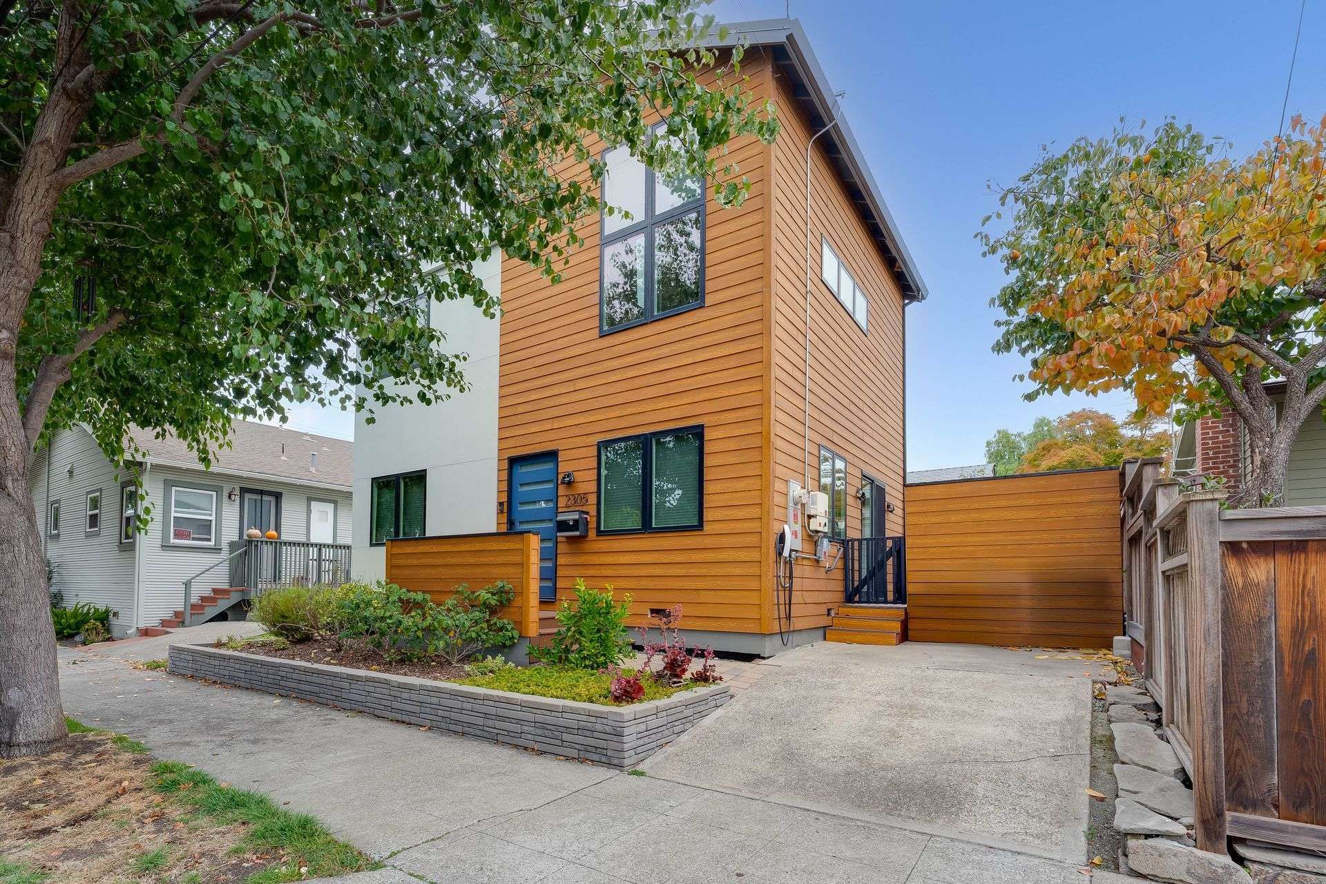 Two-story orange home with black-trimmed windows, driveway, and landscaped front yard