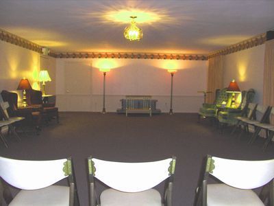 Empty lounge with chairs and lamps around a central open floor, seen from a low angle