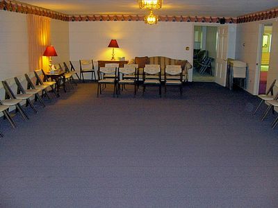 Conference room with rows of chairs, a table, lamps, and a large blue carpet