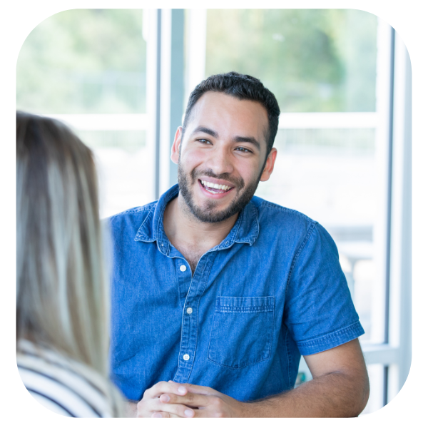 Smiling man in a blue shirt talking in a bright office setting
