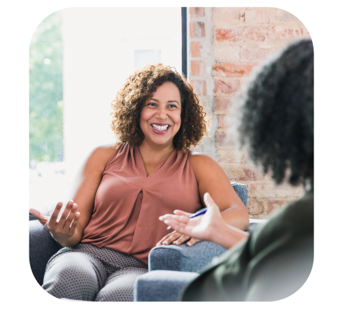 Woman smiling during a casual conversation in a bright living room with a brick wall.