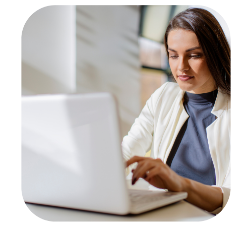 Woman using a laptop at a desk in a bright office setting