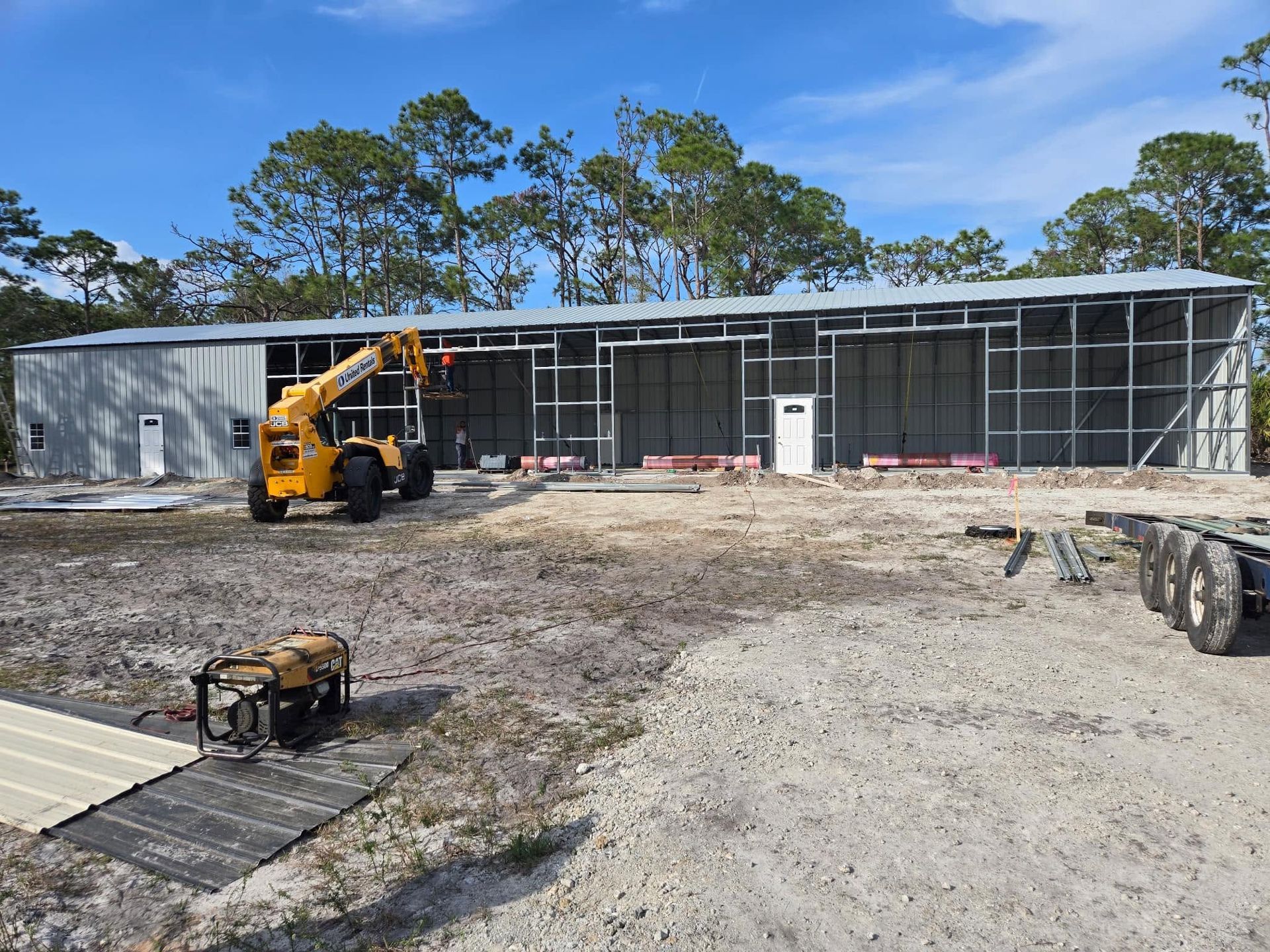 Construction site with yellow loader beside a long building under construction and scaffolding.