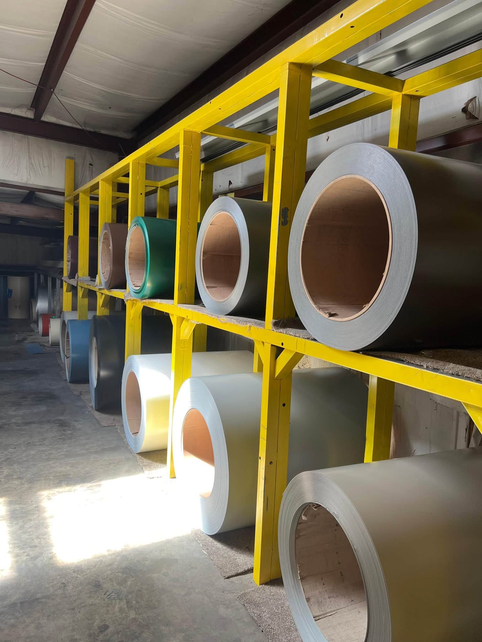 Industrial warehouse with yellow racks holding large rolls of paper or material.