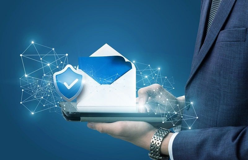 A man in a suit is holding a tablet with an envelope and a shield coming out of it.