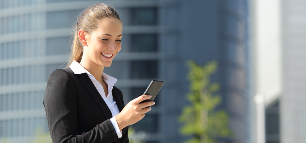 A woman in a suit is looking at her cell phone.