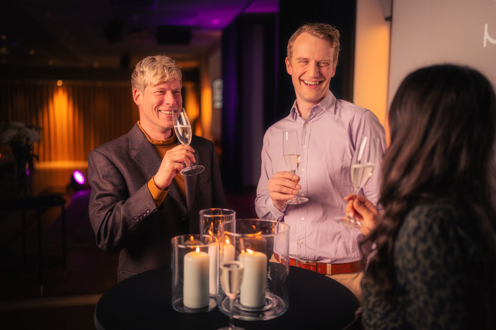 Moderne loungebar med trekrakker, hyller og varm belysning bak et hvitt flislagt gulv